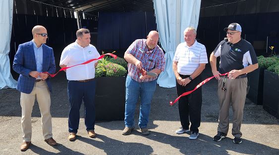 Robb Ewoldt, ISA president and soybean farmer from Davenport cuts the ribbon for the Varied Industries Tent paving project.